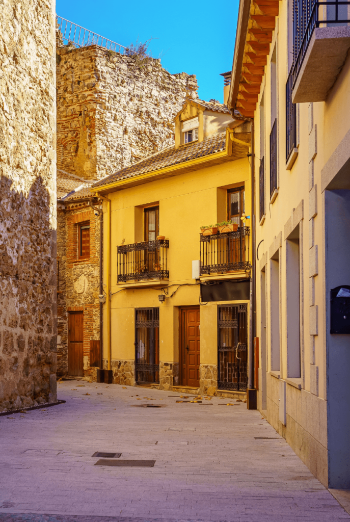 Honey-hued buildings line a narrow street in a medieval village.