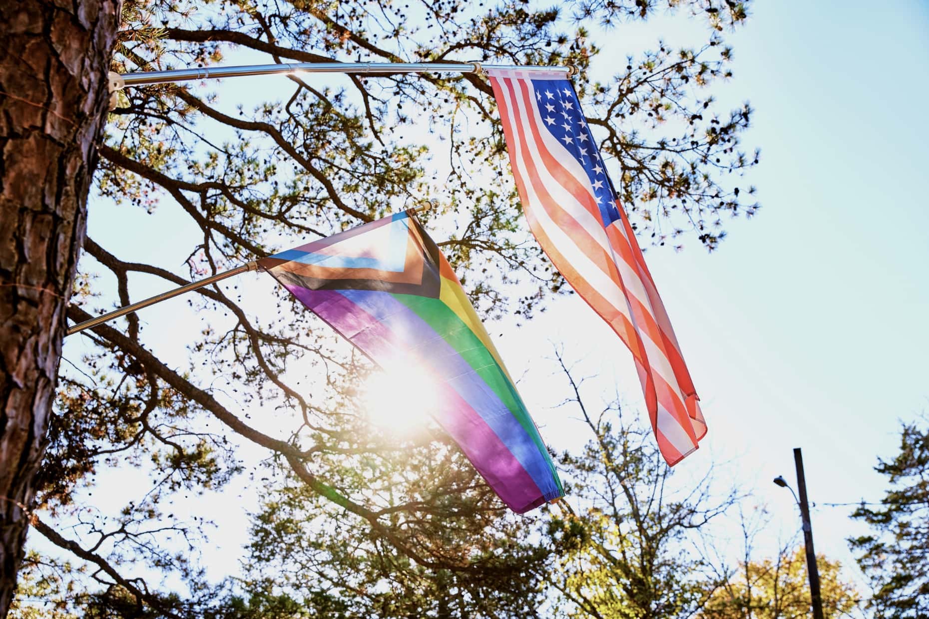 An American flag and a Progress Pride flag fly together, side by side.