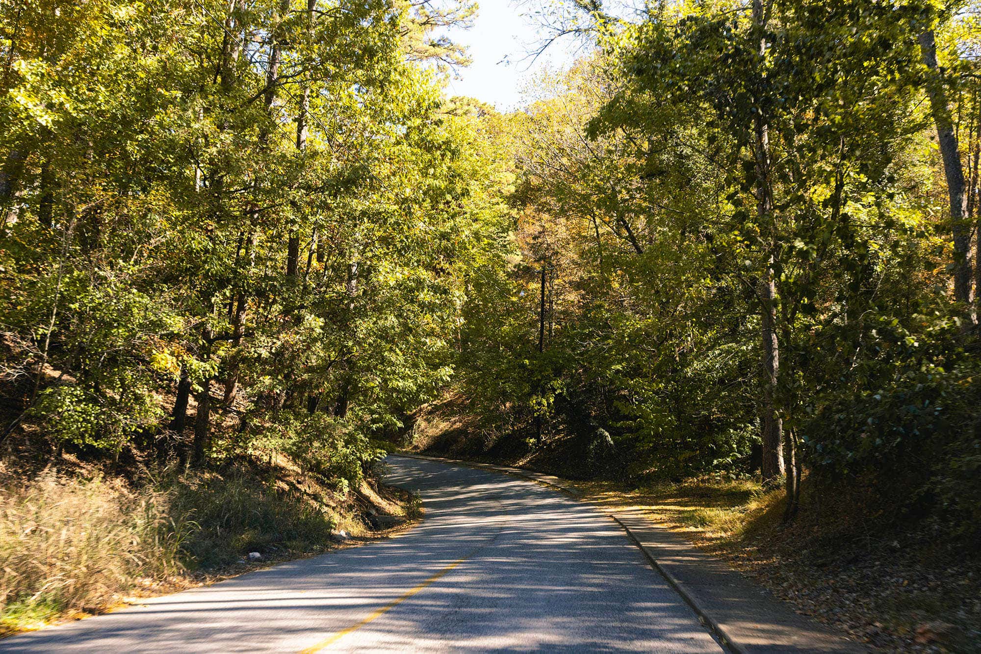 A curving two-lane highway winds through the Ozarks’ wooded hills.
