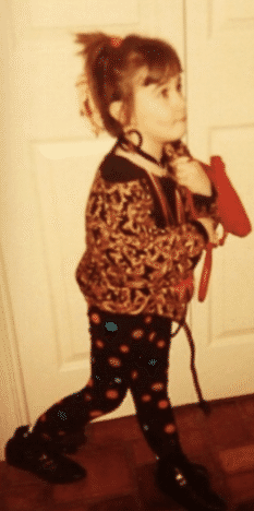 Alysse, as a child, wears an eye-catching outfit and large statement earrings.