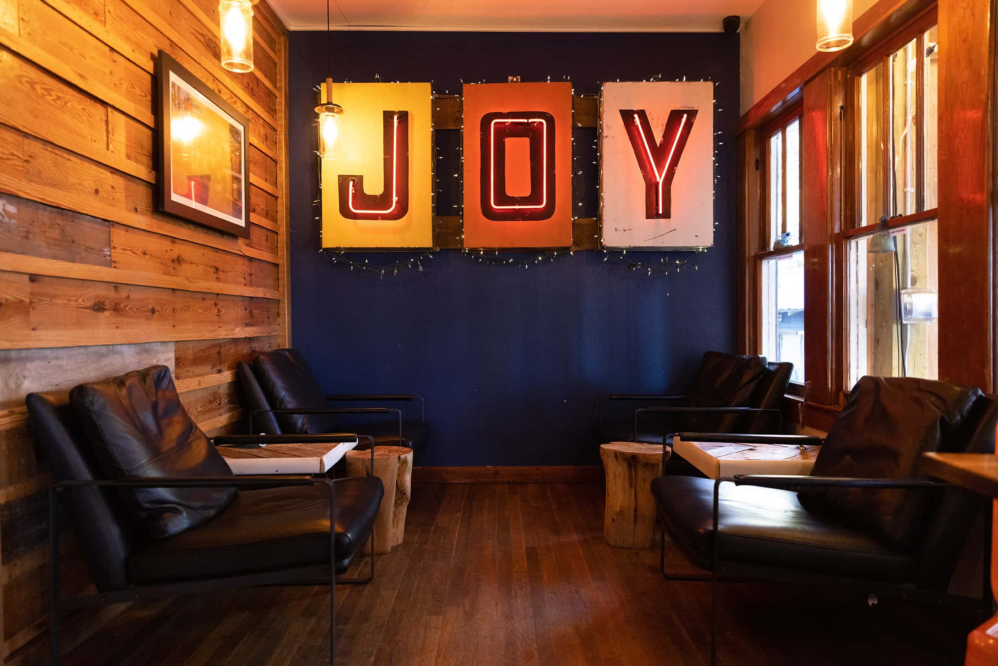 The bar’s interior, with wood-paneled walls and a neon sign that spells out 'JOY.'