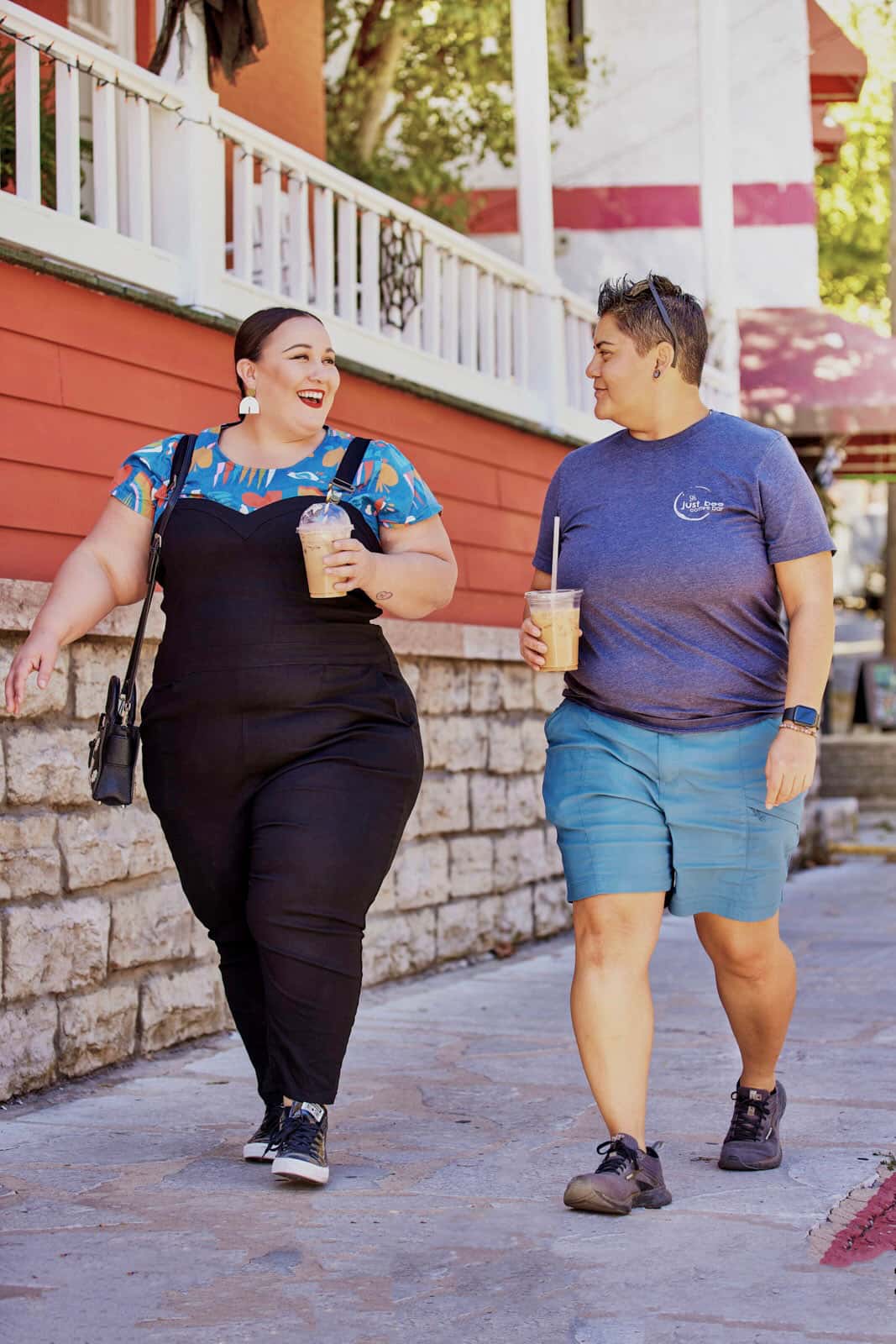 Alysse laughs as she strolls down the street with Belén, iced coffees in hand.