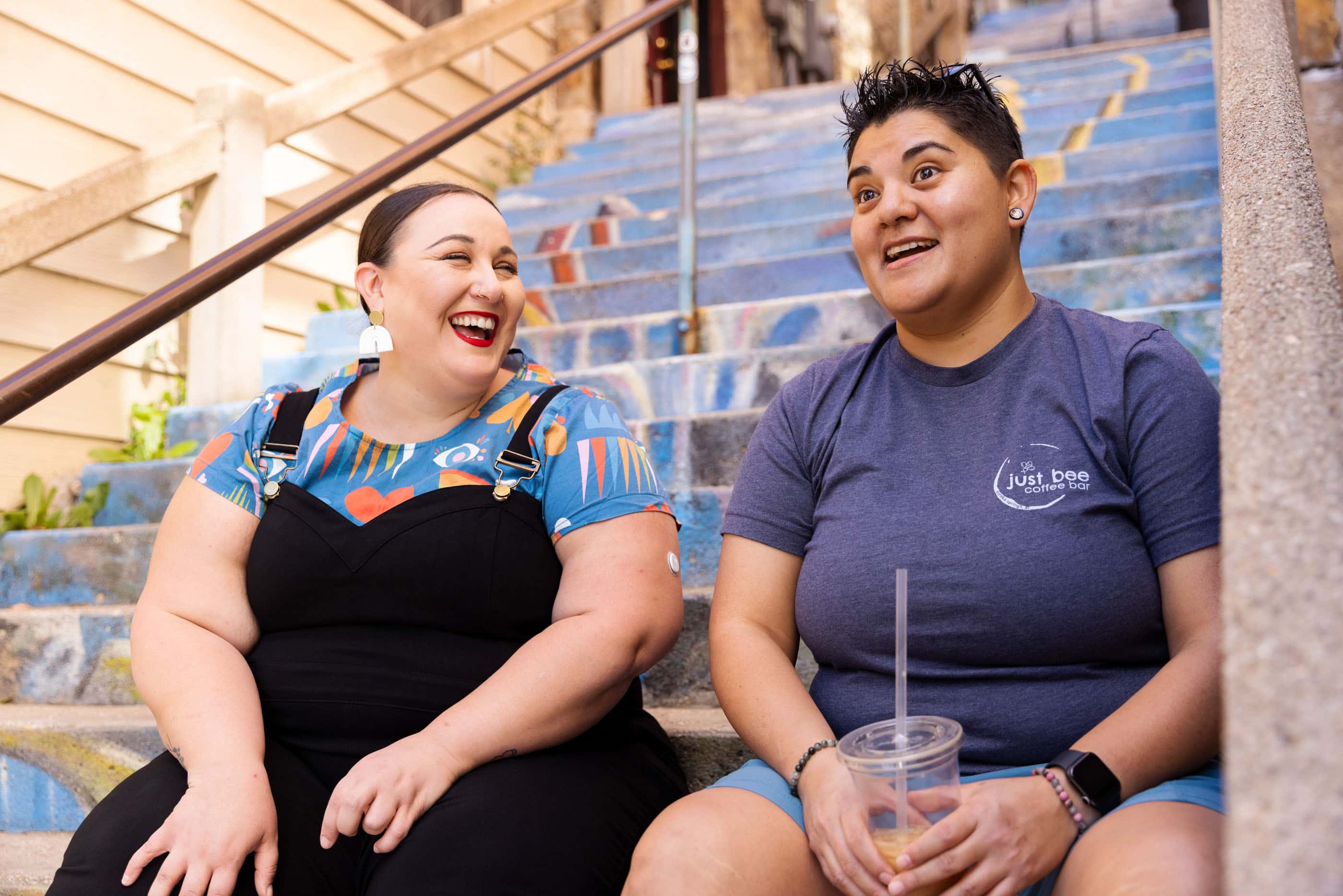 Alysse and Belen laugh together as they sit and chat on the Cash and Boardman staircase.