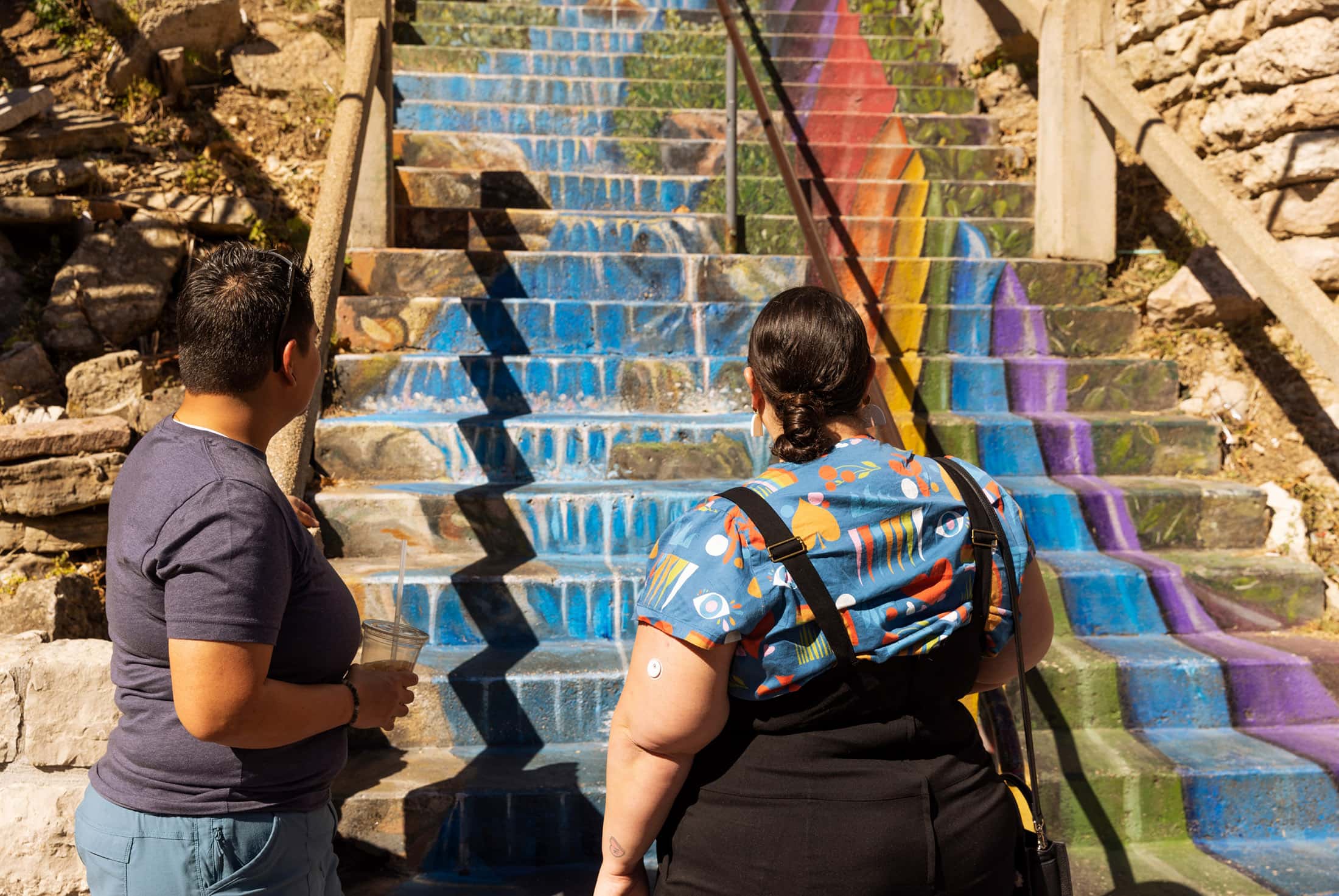 Alysse and Belén admire the Cash and Boardman staircase, which is painted with a mural that depicts a waterfall cascading down the stairs alongside a rainbow-swaddled tree.