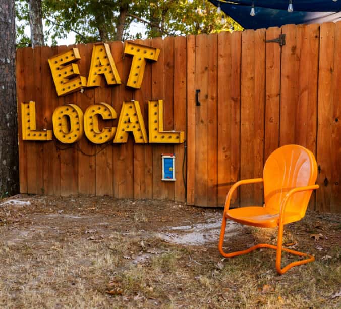 A large sign in the Three Bird Café backyard reads: Eat Local.