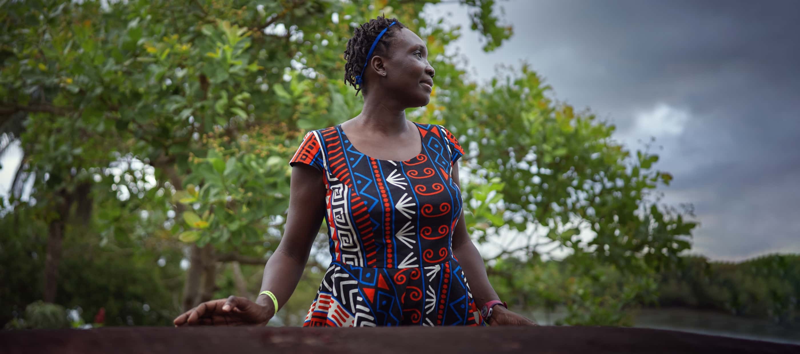 National Geographic Explorer Margaret Owuor contemplates the Muriá river, which neighbors the Curuça mangrove forest. Behind her, dark rainclouds gather.