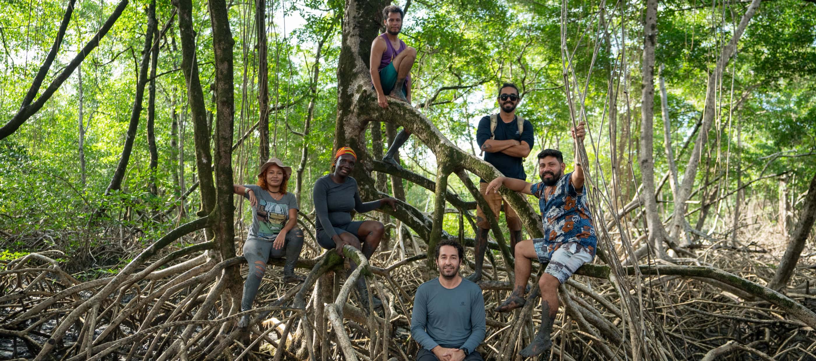 Angelo Bernardino, Margaret Owuor and several other members of their research team pose for a picture among the exposed roots of the mangrove forest.