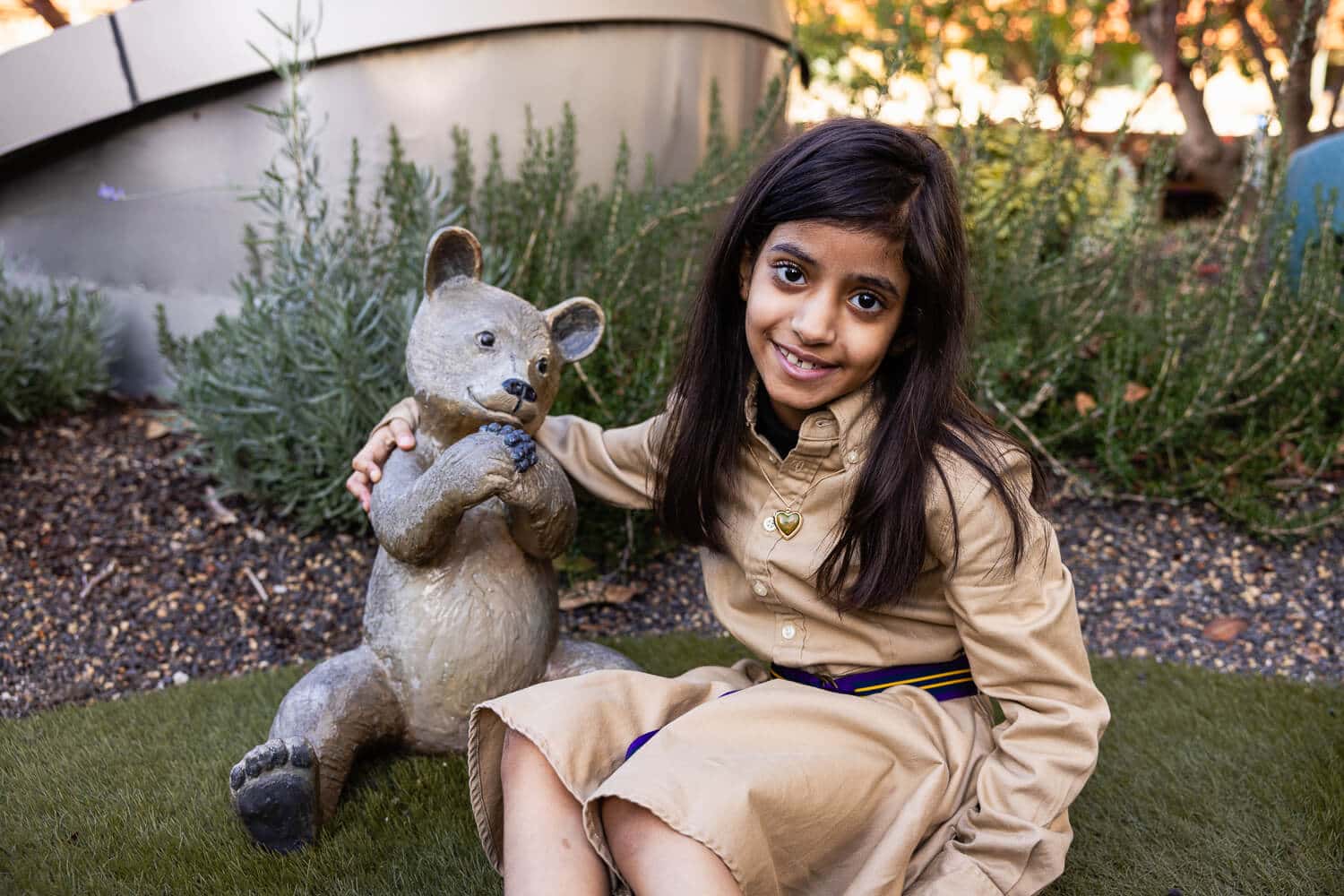 Leen with arm around teddy bear statue