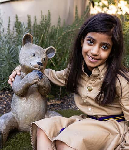 Leen with arm around teddy bear statue