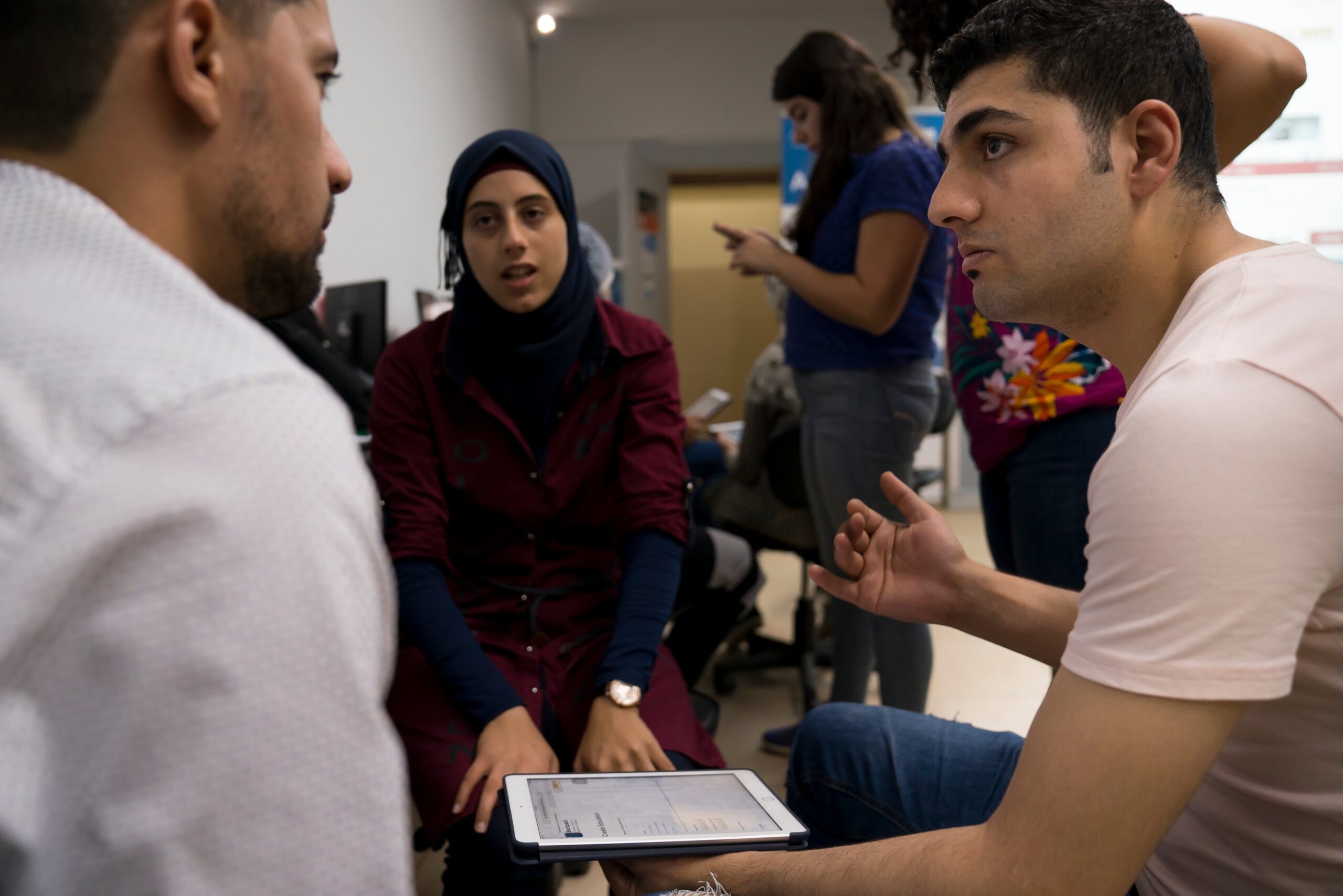 Ali Almarzouki, right, registers for the Article 26 Backpack in the Bekaa Valley with help from Eslam Abo Alhawa and friend Mohammad Alnamous. Abo Alhawa, a student at the American University of Beirut, is trained to help others create their virtual Backpacks. (Photo credit: Joe Proudman, UC Davis)