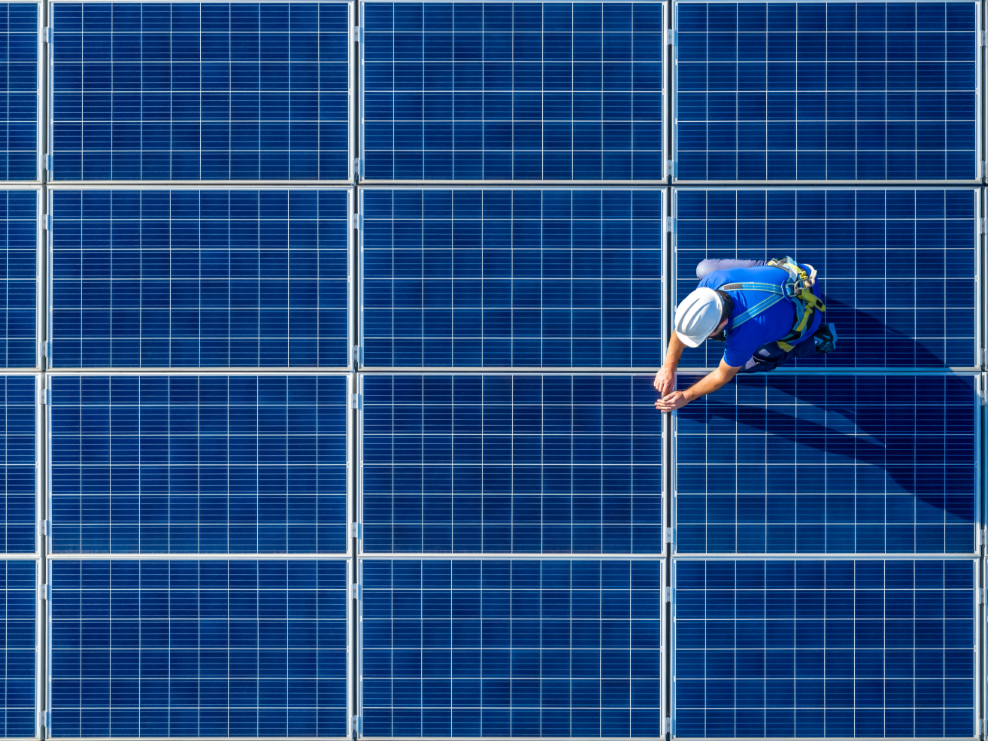A man is standing on top of a solar panel.