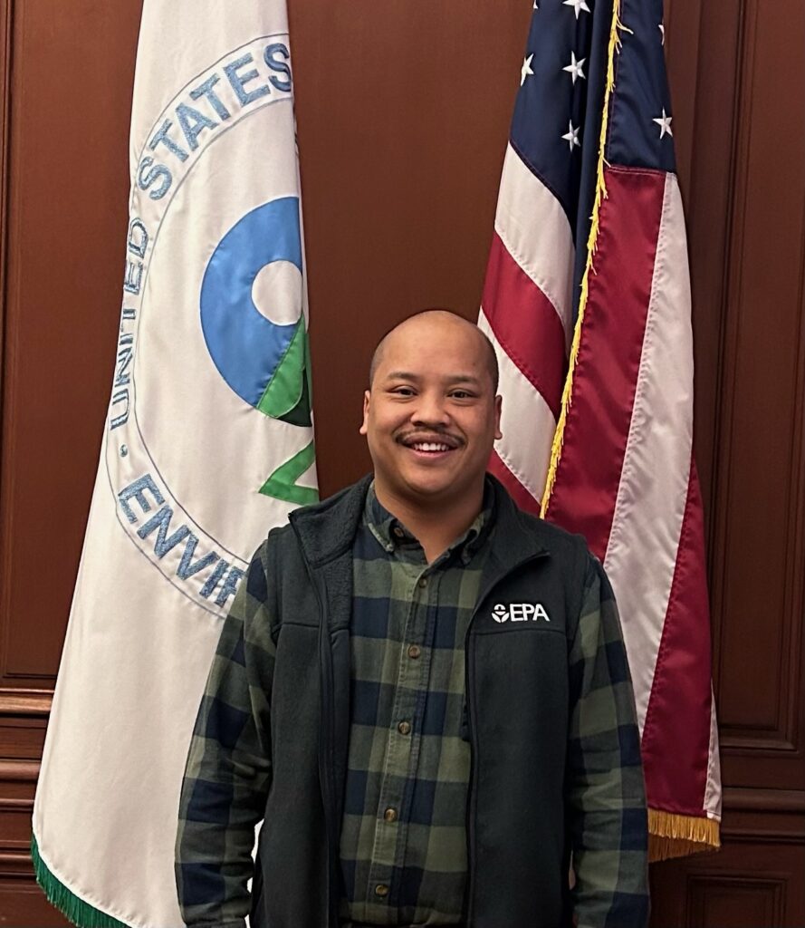 A man standing in front of two flags.