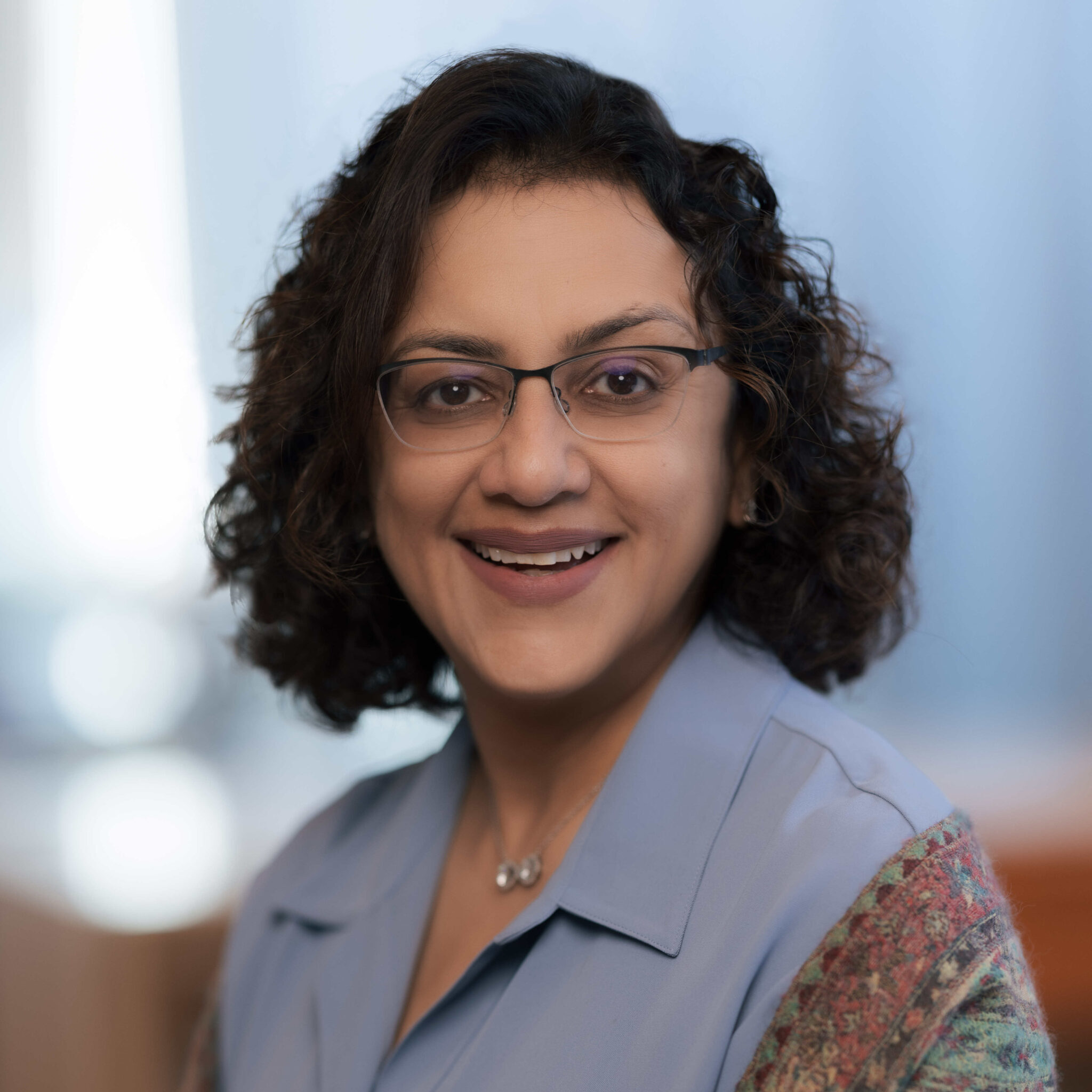 A woman wearing glasses and a blue shirt.