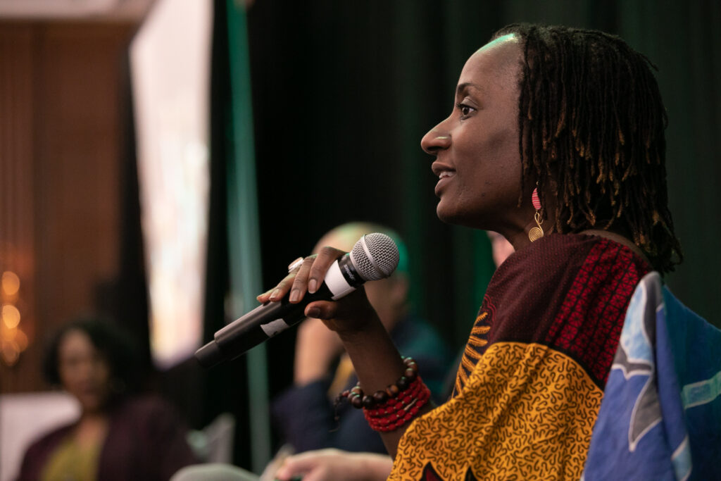 A woman with dreadlocks speaking into a microphone.