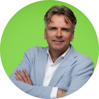 Man with light brown hair wearing a light blue blazer and white shirt, standing with arms crossed against a bright green background.
