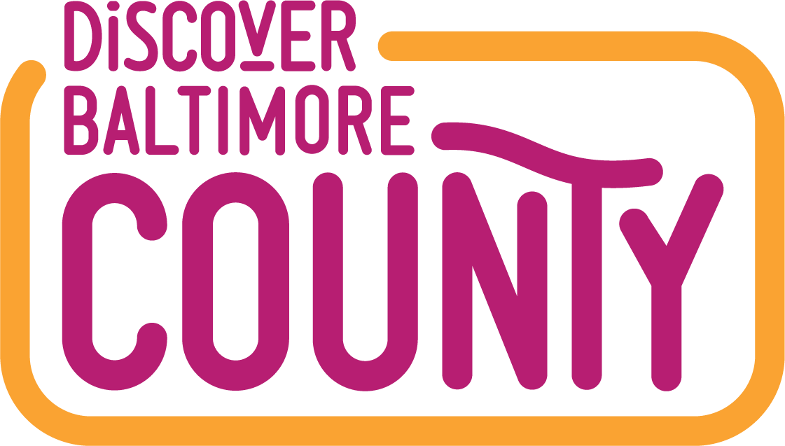 Logo for Discover Baltimore County featuring the words “Discover Baltimore” in dark pink text above the word “County” in large, bold, dark pink letters, all enclosed in a yellow rounded rectangle.